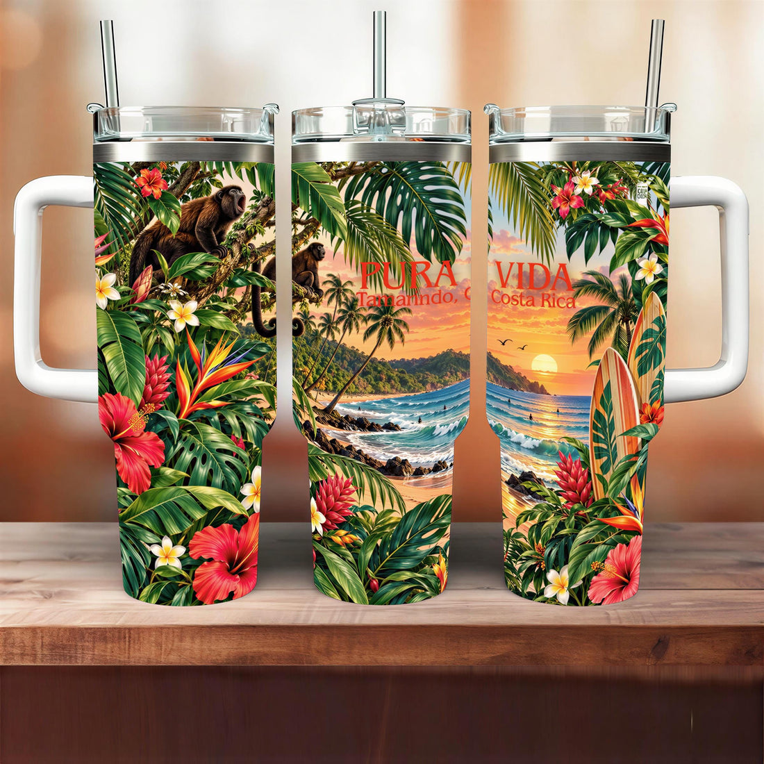 A set of three colorful tumblers with tropical designs, including palm trees, flowers, and a sunset.